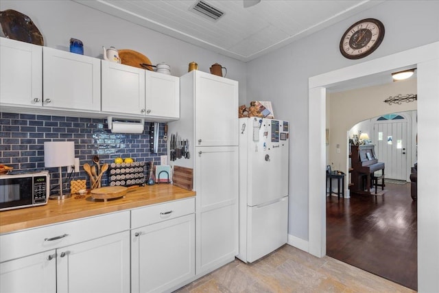 514 N Calhoun St, Perry, FL 32347 - kitchen with freestanding refrigerator, backsplash, arched walkways, and white cabinetry
