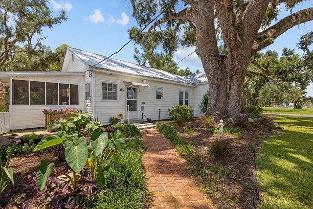 514 N Calhoun St, Perry, FL 32347 - view of front of house with a metal roof, a front yard, and a sunroom