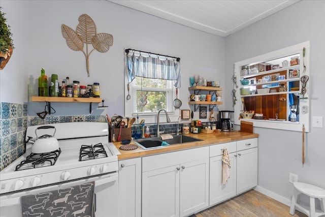514 N Calhoun St, Perry, FL 32347 - kitchen with white gas range oven, open shelves, light wood-style floors, white cabinets, and light countertops