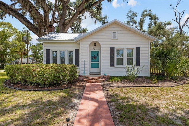 514 N Calhoun St, Perry, FL 32347 - bungalow-style home featuring a chimney, a front yard, and a metal roof