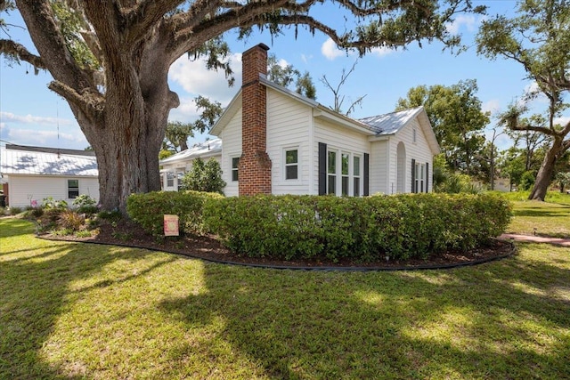 514 N Calhoun St, Perry, FL 32347 - view of property exterior featuring a chimney, a yard, and a metal roof