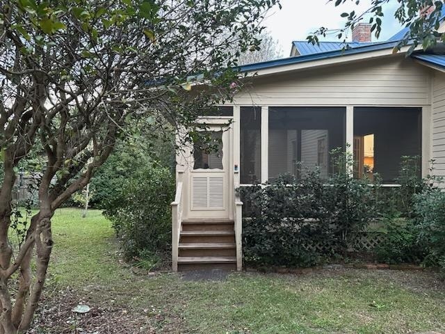 view of exterior entry featuring a lawn