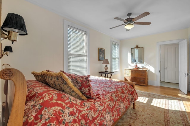 bedroom featuring ceiling fan, light wood-type flooring, and ornamental molding