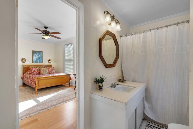 bathroom featuring ceiling fan, hardwood / wood-style floors, vanity, and ornamental molding