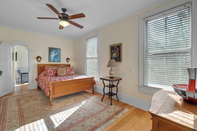 bedroom with light wood-type flooring, ceiling fan, and crown molding