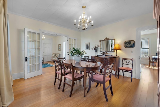 dining area with ornamental molding, a chandelier, and light wood-type flooring