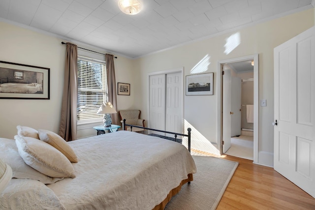 bedroom with a closet, crown molding, and light wood-type flooring