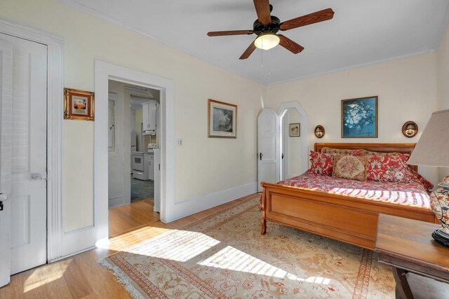 bedroom with ceiling fan, ensuite bathroom, crown molding, and light hardwood / wood-style floors