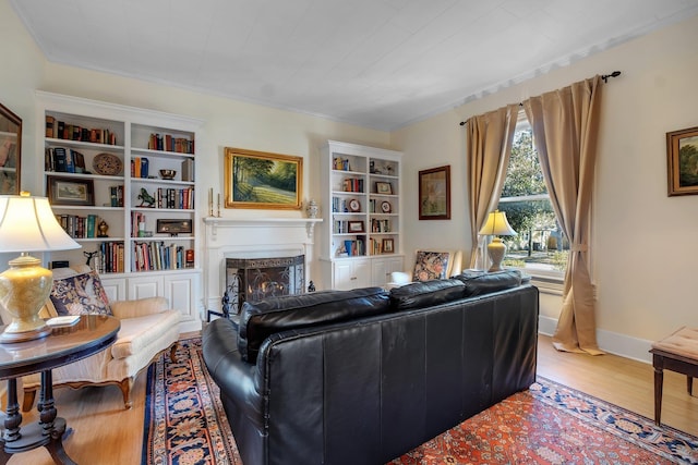 living room featuring built in shelves, wood-type flooring, and a fireplace