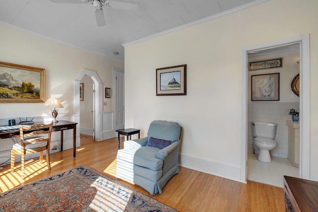 sitting room featuring ceiling fan, tile walls, crown molding, and light hardwood / wood-style flooring