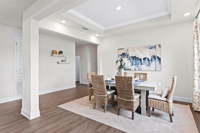 dining room featuring dark wood-type flooring and a raised ceiling