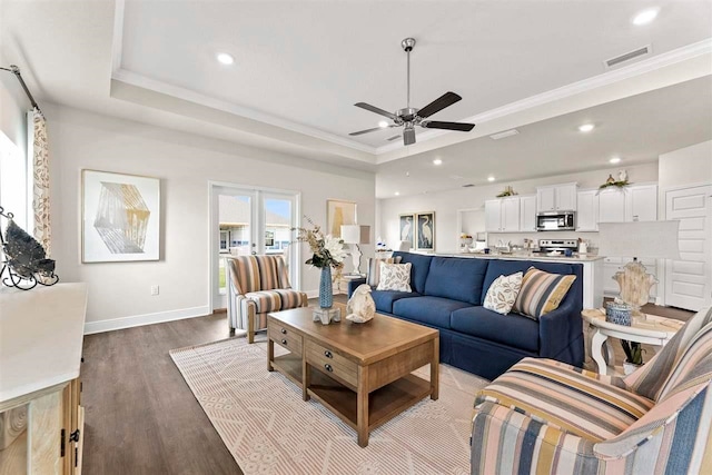 living room featuring ornamental molding, hardwood / wood-style flooring, ceiling fan, and a raised ceiling