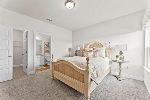 carpeted bedroom with a closet, a spacious closet, and ensuite bathroom