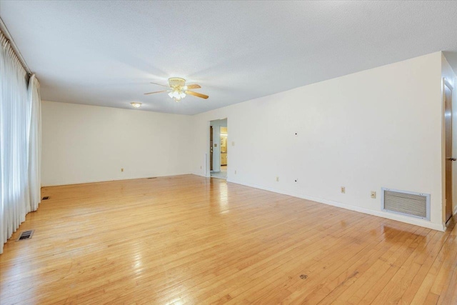 spare room featuring ceiling fan, light wood-type flooring, and a textured ceiling