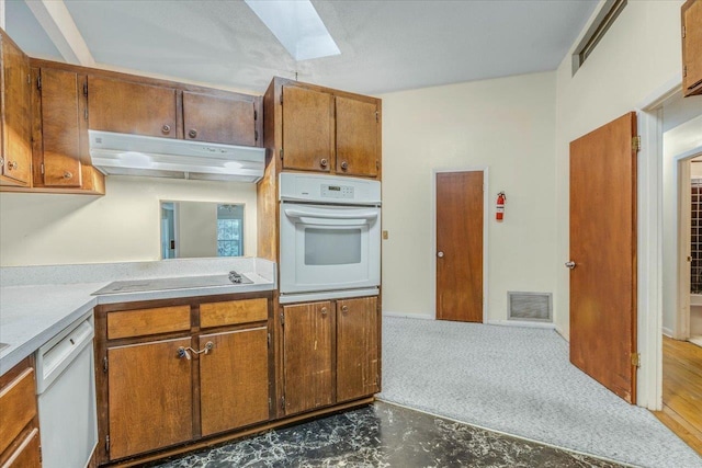 kitchen featuring a skylight, dark hardwood / wood-style floors, and white appliances