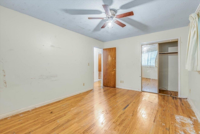 unfurnished bedroom with a textured ceiling, a closet, light hardwood / wood-style flooring, and ceiling fan