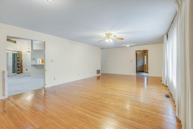 empty room featuring a wealth of natural light, ceiling fan, light hardwood / wood-style floors, and a textured ceiling