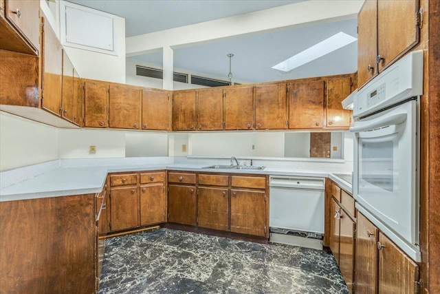 kitchen with white appliances, a skylight, and sink