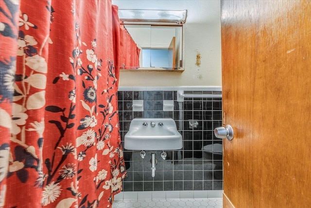 bathroom featuring tile patterned flooring, tile walls, and sink