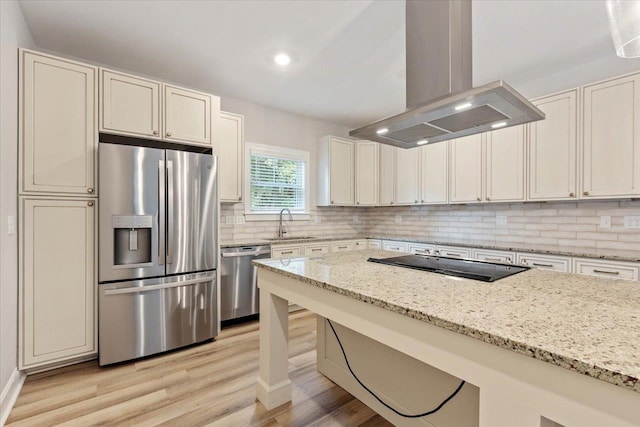 kitchen with sink, light hardwood / wood-style flooring, island range hood, light stone counters, and stainless steel appliances