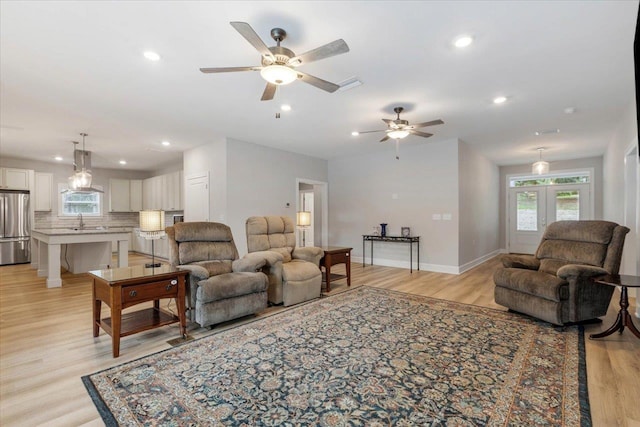 living room with french doors, light hardwood / wood-style flooring, ceiling fan, and sink