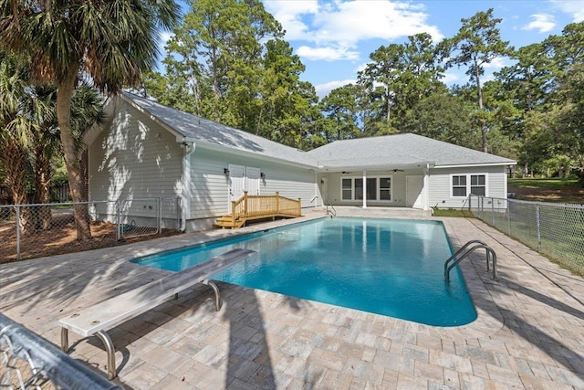 view of swimming pool featuring ceiling fan, a patio, and a diving board