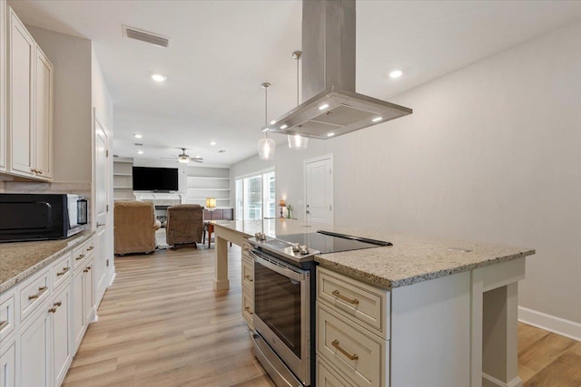 kitchen featuring ceiling fan, pendant lighting, stainless steel range with electric stovetop, island range hood, and a kitchen island