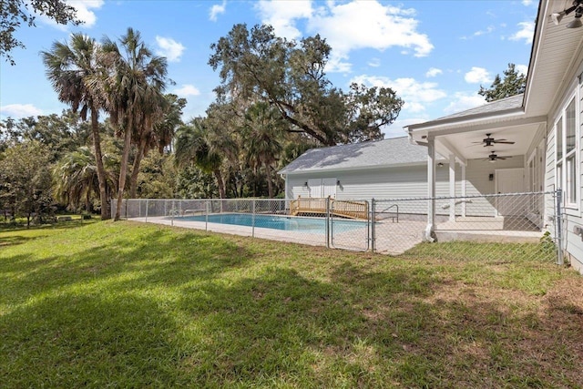 view of pool with ceiling fan and a lawn