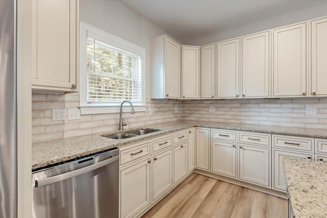 kitchen featuring light stone counters, dishwasher, light wood-type flooring, and sink