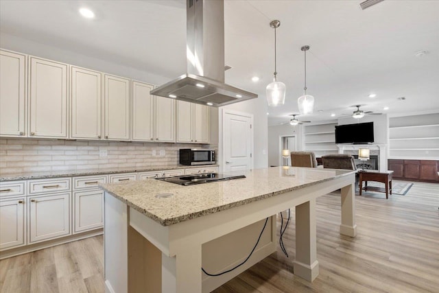 kitchen featuring island exhaust hood, black electric stovetop, light stone countertops, and pendant lighting