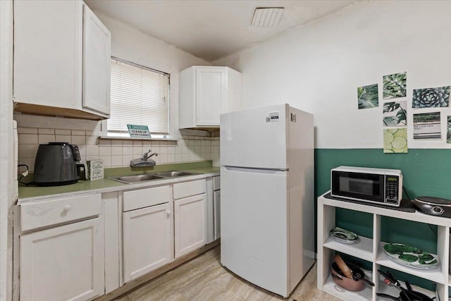 kitchen featuring white cabinetry, white refrigerator, sink, and backsplash