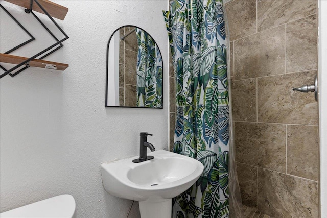 bathroom featuring a shower with shower curtain, sink, and toilet