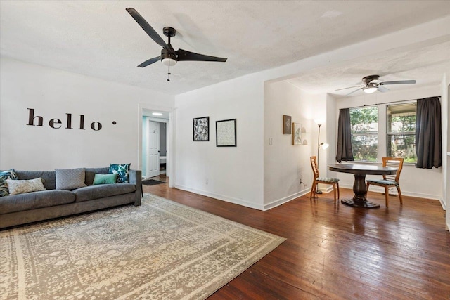 living room featuring ceiling fan, dark wood-type flooring, and a textured ceiling