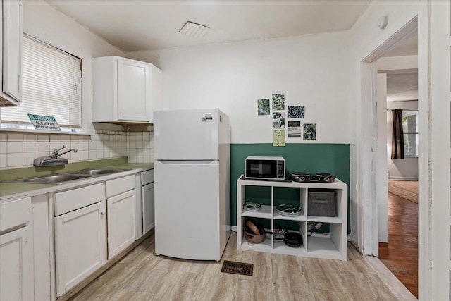 kitchen featuring white fridge, light hardwood / wood-style flooring, sink, and white cabinets