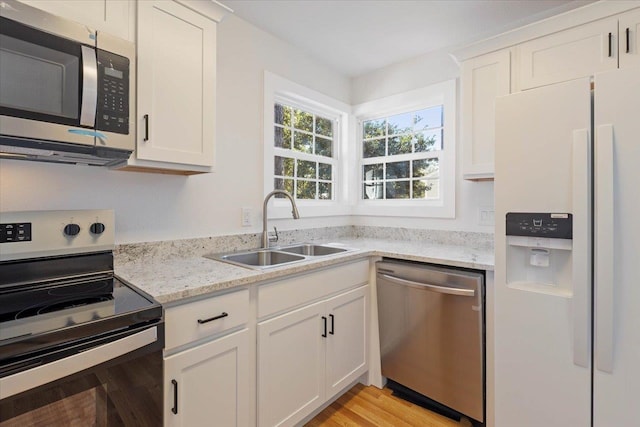 kitchen with white cabinets, light wood-type flooring, stainless steel appliances, and sink