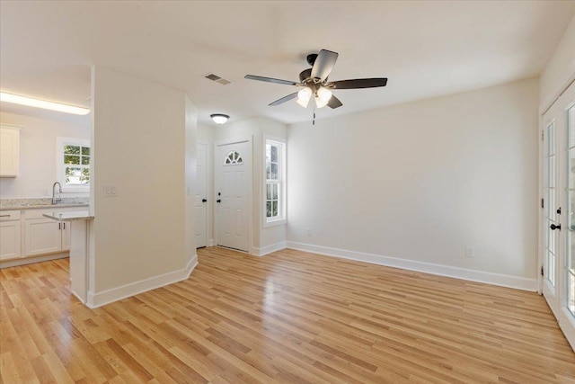 unfurnished room with light wood-type flooring, sink, and ceiling fan