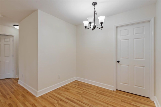 spare room featuring light hardwood / wood-style floors and an inviting chandelier