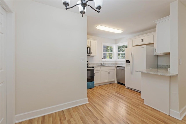 kitchen with stainless steel appliances, light wood-type flooring, white cabinetry, light stone countertops, and sink