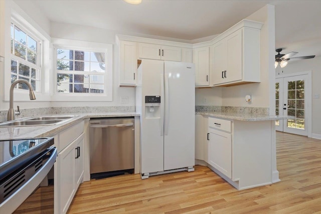 kitchen with white refrigerator with ice dispenser, white cabinetry, light wood-type flooring, sink, and stainless steel dishwasher