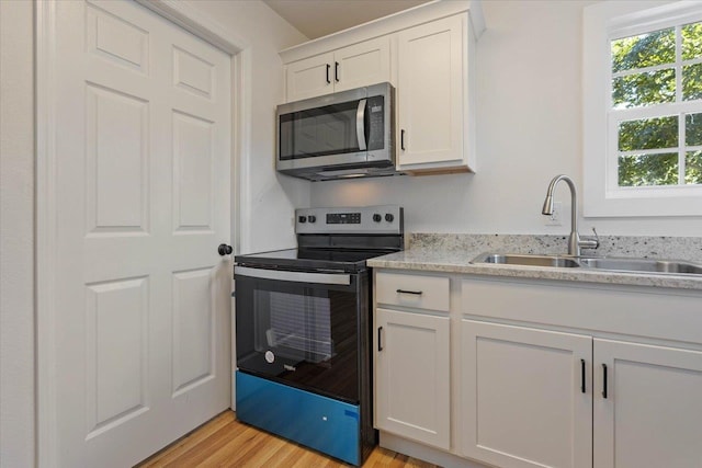 kitchen with white cabinetry, light wood-type flooring, sink, and black range with electric stovetop