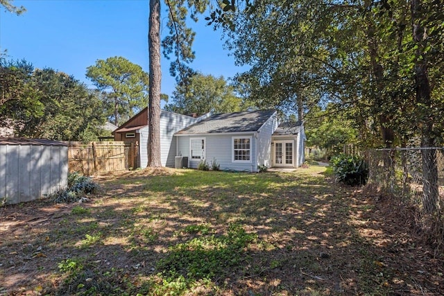 rear view of house featuring central AC, a lawn, and a storage shed