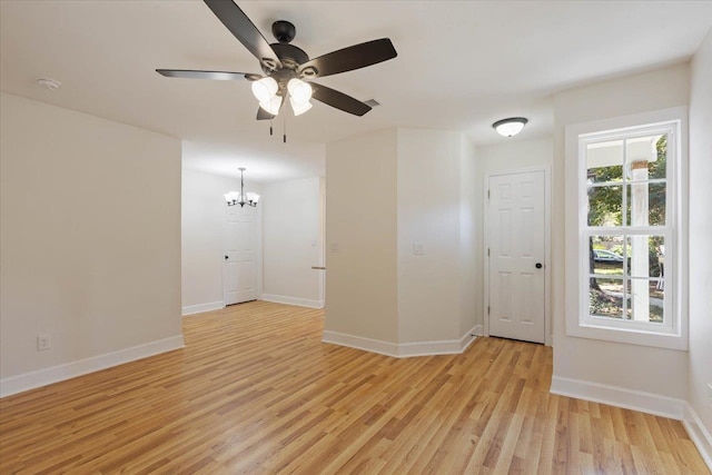 unfurnished room with light wood-type flooring and ceiling fan with notable chandelier