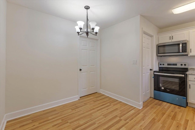 kitchen featuring appliances with stainless steel finishes, an inviting chandelier, light hardwood / wood-style floors, and white cabinets