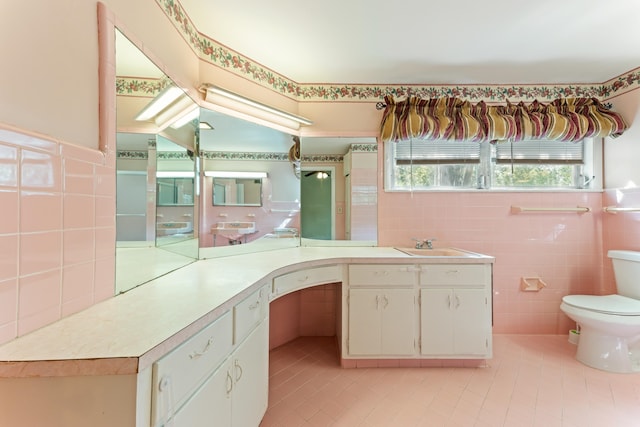 bathroom featuring tile walls, toilet, tile patterned floors, and a sink