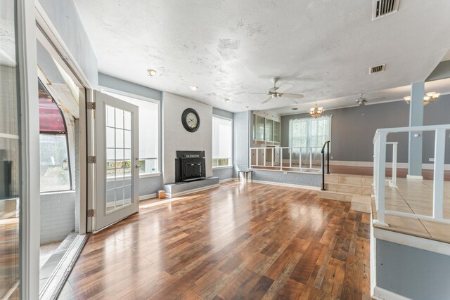 unfurnished living room featuring wood finished floors, a textured ceiling, ceiling fan, and visible vents