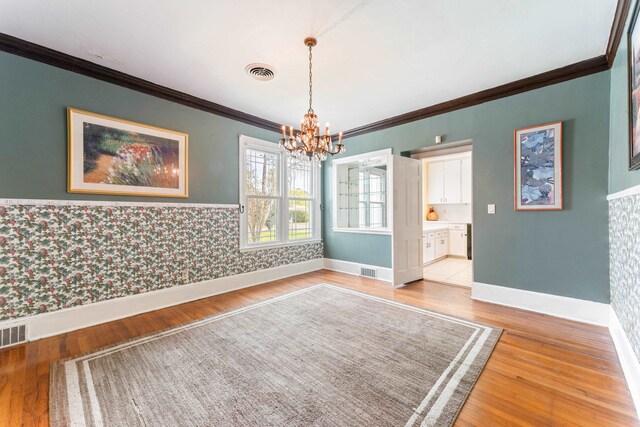 unfurnished dining area featuring visible vents, light wood-style flooring, wallpapered walls, and an inviting chandelier