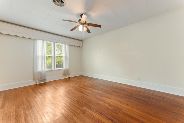 spare room featuring wood finished floors, baseboards, ceiling fan, and visible vents