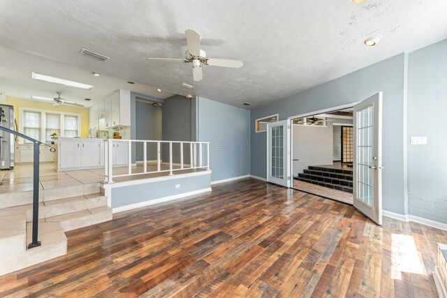 unfurnished living room with stairs, ceiling fan, and wood-type flooring
