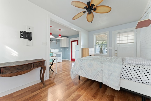 bedroom featuring freestanding refrigerator, light wood-style flooring, and a ceiling fan