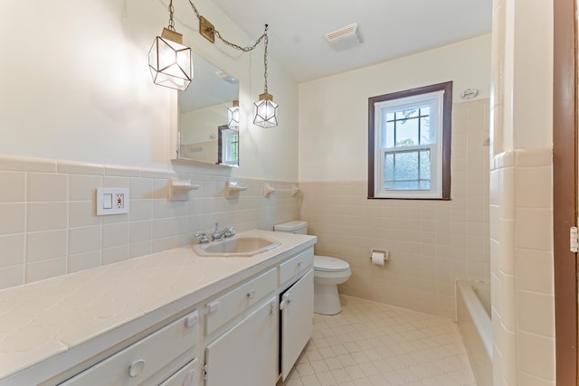 full bathroom featuring a wainscoted wall, toilet, vanity, visible vents, and tile walls